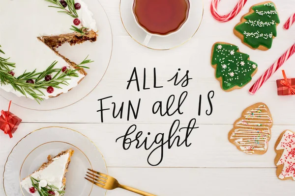 Top view of christmas pie with rosemary, cup of tea and christmas tree cookies on white wooden table with all is fun all is bright illustration — Stock Photo