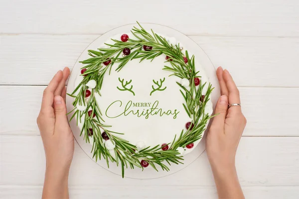 Cropped view of woman holding christmas pie with Merry Christmas lettering, rosemary and cranberries — Stock Photo