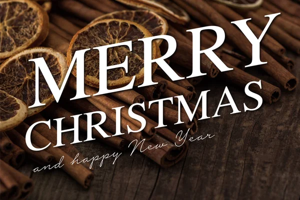 Close up view of dried orange slices and cinnamon on wooden background with merry Christmas and happy new year illustration — Stock Photo