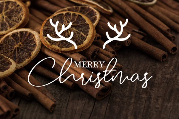 Vista de cerca de rebanadas de naranja seca y canela sobre fondo de madera con feliz ilustración de Navidad — Stock Photo