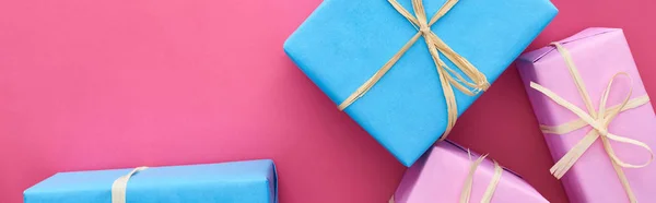 Panoramic shot of blue and pink presents on crimson — Stock Photo