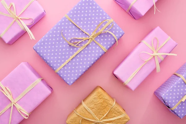 Vue de dessus des boîtes-cadeaux colorées et enveloppées sur rose — Photo de stock