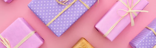 Plan panoramique de boîtes-cadeaux colorées et enveloppées isolées sur rose — Photo de stock