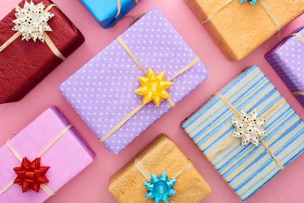 Draufsicht auf bunte und verpackte Geschenkboxen mit Schleifen auf rosa — Stockfoto