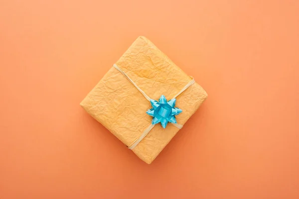 Vista superior de la caja de regalo con arco azul aislado en naranja - foto de stock