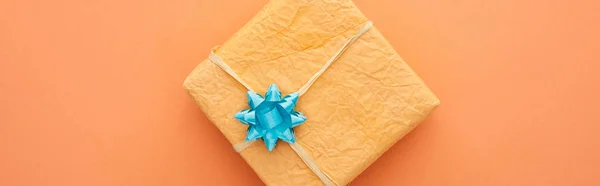 Panoramic shot of gift box with blue bow isolated on orange — Stock Photo