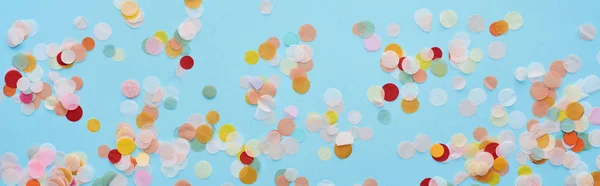 Panoramic shot of multicolored confetti on blue — Stock Photo