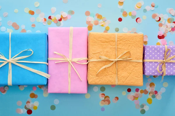 Top view of wrapped gift boxes near confetti on blue — Stock Photo