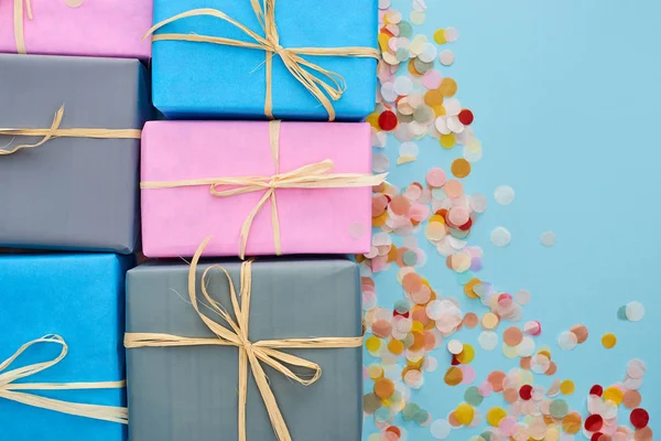 Draufsicht auf bunte und verpackte Geschenke in der Nähe von Konfetti auf blau — Stockfoto