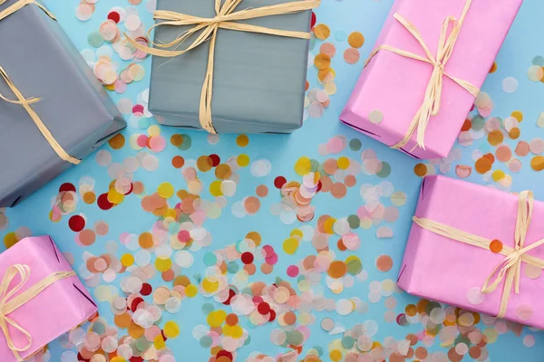 Top view of colorful wrapped presents near confetti on blue — Stock Photo