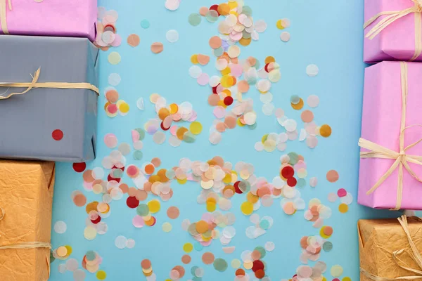 Top view of wrapped gifts near confetti on blue — Stock Photo