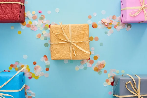 Top view of wrapped presents near colorful confetti on blue — Stock Photo