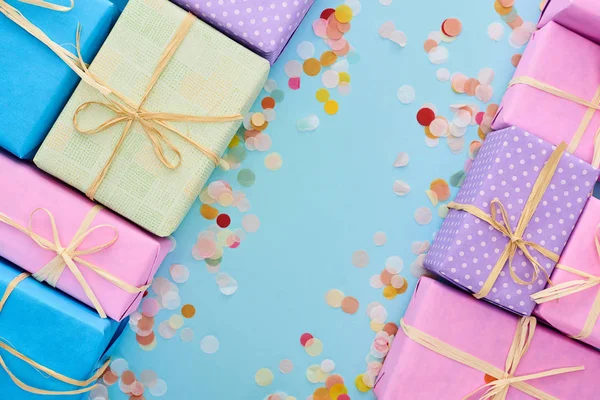 Top view of wrapped gifts near colorful confetti on blue — Stock Photo