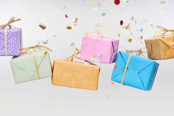 Confettis tombant près de cadeaux colorés et enveloppés sur blanc — Photo de stock