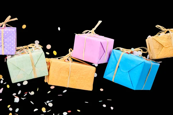 Falling confetti near colorful gifts on black — Stock Photo