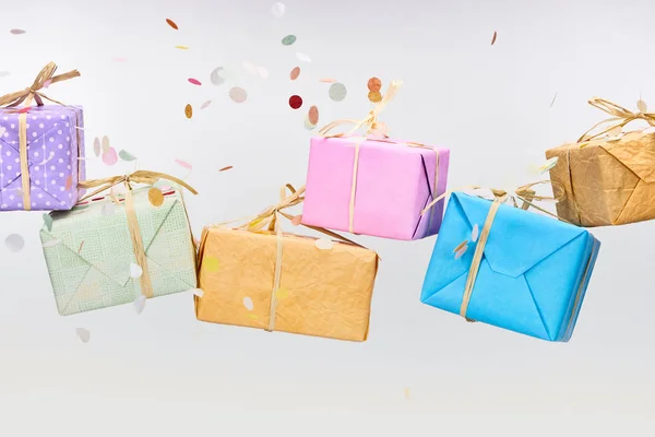 Falling confetti near colorful presents on white — Stock Photo