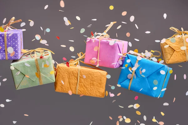 Falling confetti near colorful presents on grey — Stock Photo