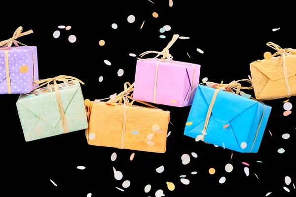 Falling confetti near colorful gift boxes on black — Stock Photo