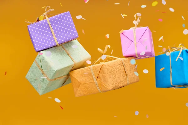 Falling confetti near colorful presents on orange — Stock Photo