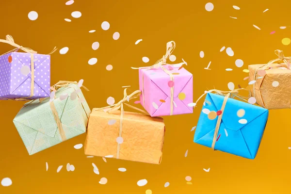 Falling confetti near colorful gifts on orange — Stock Photo