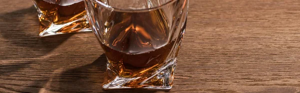 Foto panorámica de brandy en vasos con sombra sobre mesa de madera - foto de stock