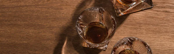 Top view of brandy in glasses and decanter on wooden table, panoramic shot — Stock Photo