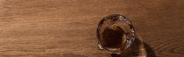 Top view of brandy in glass on wooden table, panoramic shot — Stock Photo