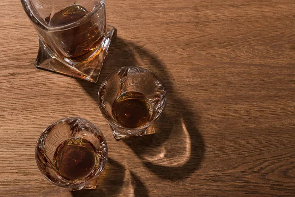Vista superior de brandy en vasos y decantador sobre mesa de madera - foto de stock