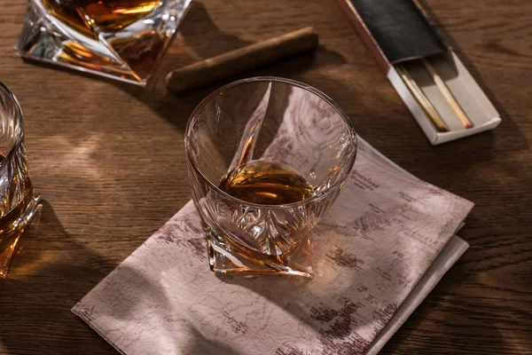 Бренди в стаканах с картой, сигарой и спичками на деревянном столе — стоковое фото