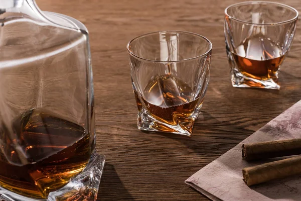 Copas de brandy con decantador y cigarros en el mapa en la mesa de madera — Stock Photo