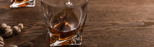 Gläser Brandy mit Pistazien auf Holztisch, Panoramaaufnahme — Stockfoto