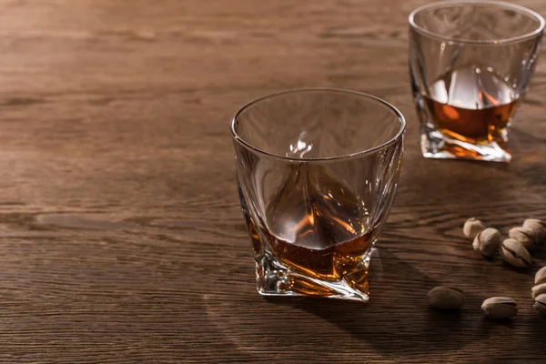 Gläser Brandy mit Pistazien auf Holztisch — Stockfoto