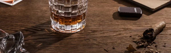 Copa de brandy con cigarro, encendedor y libro sobre mesa de madera, plano panorámico - foto de stock