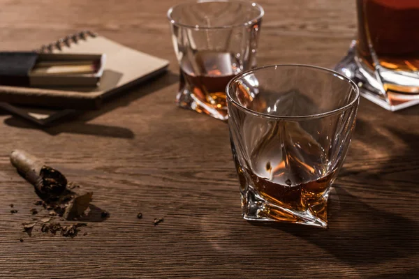 Selective focus of brandy in glasses with cigars, lighter and matches on wooden table — Stock Photo