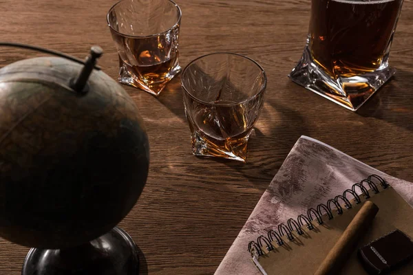 Selective focus of brandy in glasses with cigar, globe and map on wooden table — Stock Photo