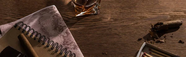 Brandy with map, cigars and matches on wooden table, panoramic shot — Stock Photo