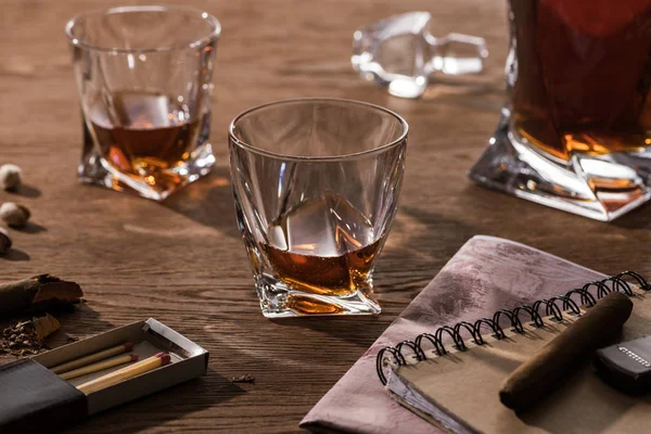 Glasses of brandy, cigars with map and pistachios on wooden table — Stock Photo