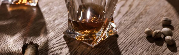 Colpo panoramico di brandy, sigari e pistacchi sul tavolo di legno — Foto stock