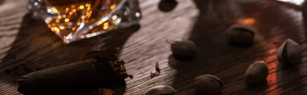 Copo de conhaque com charuto e pistache na mesa de madeira, tiro panorâmico — Fotografia de Stock