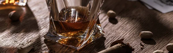Bicchiere di brandy con sigaro e pistacchi su tavolo in legno, colpo panoramico — Foto stock