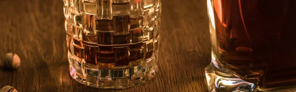 Bicchiere di brandy con decanter e pistacchi su tavolo in legno, colpo panoramico — Foto stock