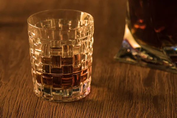 Glass on brandy with decanter on background on wooden table — Stock Photo