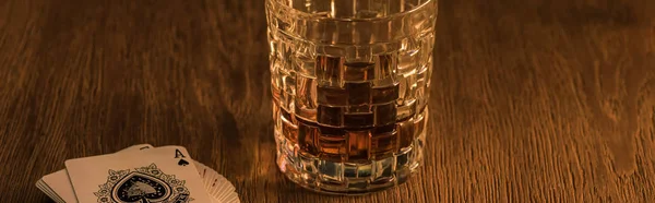 KYIV, UCRANIA - 7 DE NOVIEMBRE DE 2019: Vaso sobre brandy y cartas sobre mesa de madera, plano panorámico - foto de stock