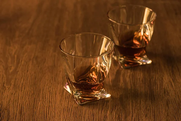 Two glasses of brandy on wooden table — Stock Photo