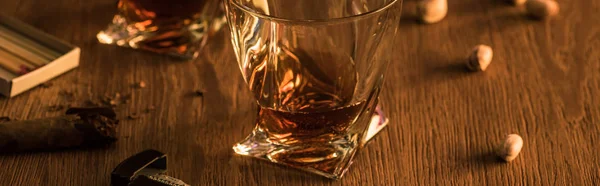 Glasses of brandy with pistachios, cigar and matches on wooden table, panoramic shot — Stock Photo