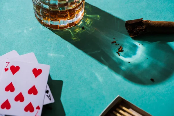 KYIV, UKRAINE - NOVEMBER 7, 2019: Glass of brandy with cigar and playing cards on green background — Stock Photo