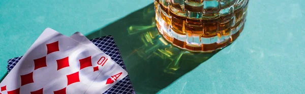 KYIV, UKRAINE - NOVEMBER 7, 2019: Glass of brandy with playing cards on green background, panoramic shot — Stock Photo