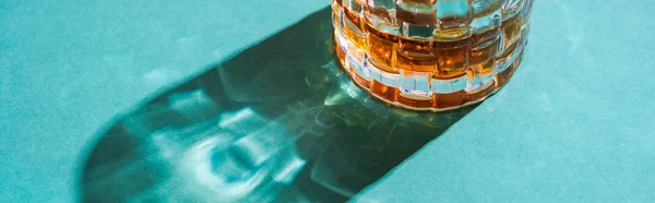 Glass of brandy on green background, panoramic shot — Stock Photo