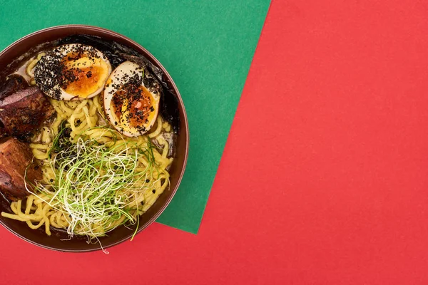 Vista superior de ramen de carne picante na superfície verde e vermelha — Fotografia de Stock