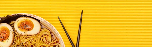 Top view of seafood ramen near chopsticks on yellow surface, panoramic shot — Stock Photo